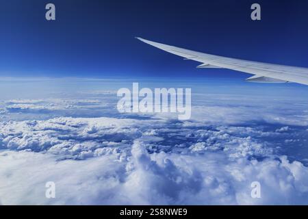 View from the aircraft window during a flight over India with the airline Etihad. Blue sky and cloud structures over the sea, wing of a Boeing 787 air Stock Photo