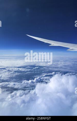 View from the aircraft window during a flight over India with the airline Etihad. Blue sky and cloud structures over the sea, wing of a Boeing 787 air Stock Photo