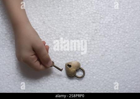 Hand holding a heart shaped lock and key on a white background Stock Photo