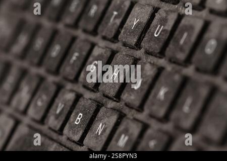 front view closeup of old black keyboard with keys covered in dust and dirt isolated on white background Stock Photo