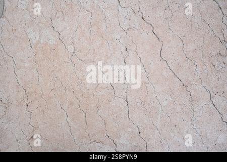 A detailed closeup of light beige stone surface showcasing visible cracks and textured patterns Stock Photo