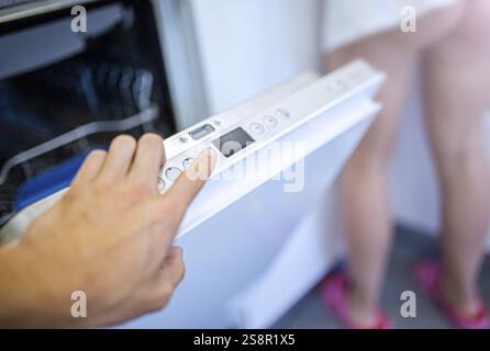 Hand pressing buttons on a dishwasher's control panel Stock Photo