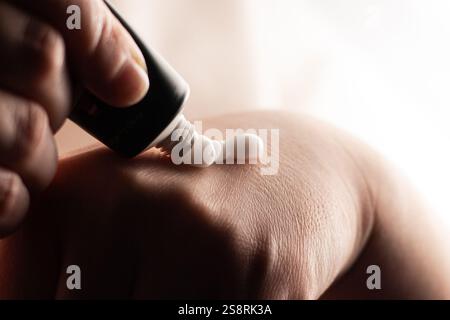 Female squeezing cream out of tube. Applying hand cream on hand. Close up image of white cream. Soft hands and skincare concept. Stock Photo