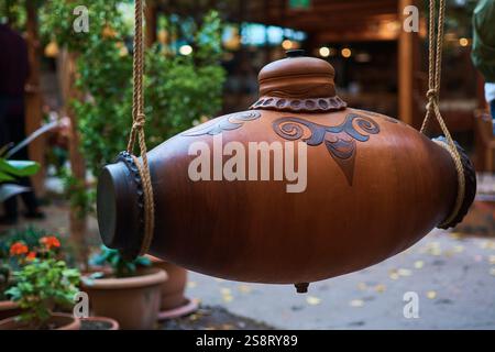 large clay bottle of wine hangs on ropes Stock Photo