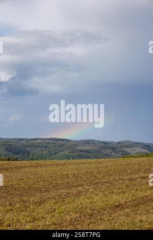 A rainbow is seen in the sky above a field Stock Photo