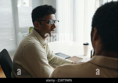 Rear view of two colleagues having conversation at table during meeting Stock Photo