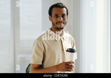 Portrait of African American businessman drinking coffee while standing in office Stock Photo