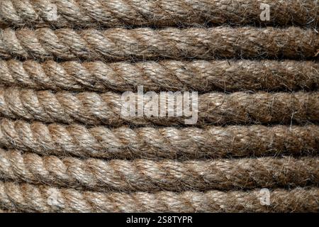 Natural jute hemp rope rolled into a coil, close up. Brown spool of linen rope texture on the background Stock Photo