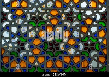 Perforated stucco window decorated with colorful stained glass with floral patterns on a building on the street in the resort town of Sharm El Sheikh, Stock Photo