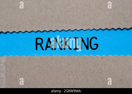 Ranking message written on ripped torn paper on blue background. Conceptual ranking symbol. Copy space. Stock Photo