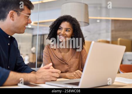 Two happy busy diverse professional business team colleagues working on laptop. Stock Photo
