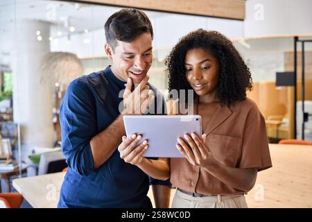 Busy business man and business woman standing in office using tablet talking. Stock Photo