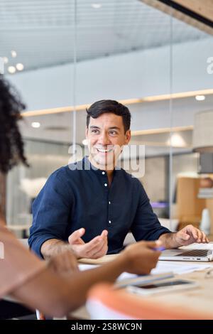 Young happy Hispanic business man manager working with colleague at meeting. Stock Photo