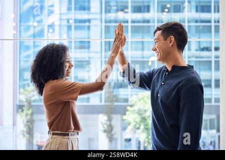 Two happy diverse young team business people give high five standing in office. Stock Photo