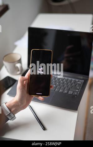 woman using phone showing  application on screen and laptop Stock Photo