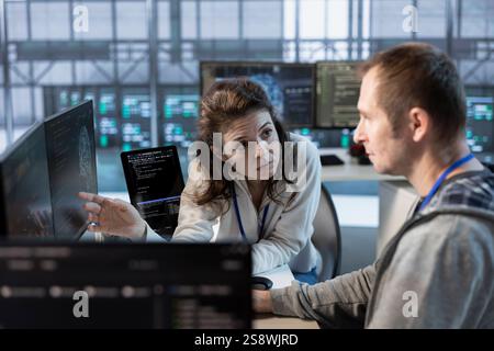 Teamworking colleagues using machine learning to optimize data center operations, improving efficiency of infrastructure. Manager discussing with worker, implementing server virtualization Stock Photo