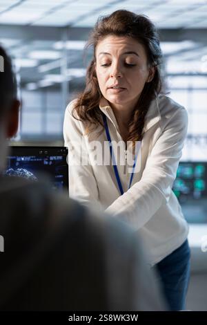 Manager overseeing workers in data center, coordinating deployment of server architecture, improving data processing. Supervisor checking progress done by employees in server farm testing equipment Stock Photo
