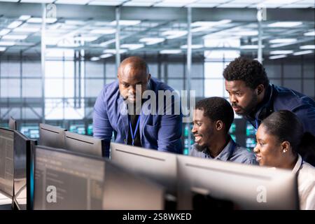 Management executive checking on data center employees creating technical documentation for software applications. Team leader supervising IT workers in server room maintaining databases Stock Photo