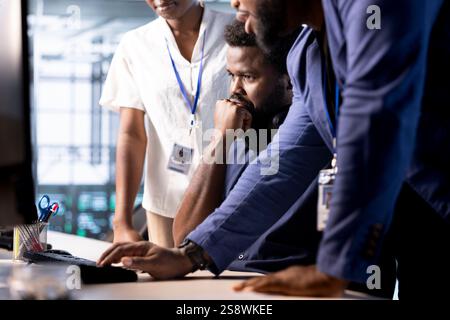 Team of data center program developers creating technical documentation for software applications. System administrators in server room using computer, maintaining databases Stock Photo