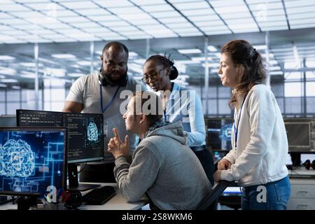 Manager doing team meeting with technicians, delegating tasks in high tech data center office. Supervisor doing brainstorming with IT specialists, telling them how to monitor AI supercomputers Stock Photo