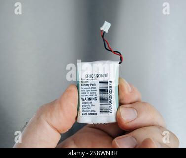 Paris, France - Apr 25, 2024: A close-up of an Ericsson Ni-MH rechargeable battery pack with a warning label, held in hand, featuring exposed wires ag Stock Photo