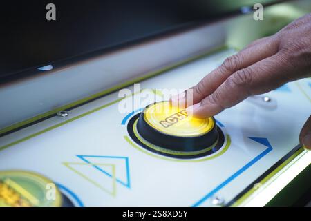A CloseUp of a Hand Delicately Pressing a Colorful Button on a CandyThemed Arcade Machine Stock Photo