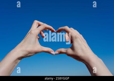 Two hands forming a heart shape in the sky. Concept of love and warmth Stock Photo