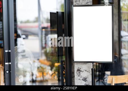 Mockup white poster with black frame stand in front of blur restaurant cafe background for show or present promotion product concept. Standing mockup Stock Photo