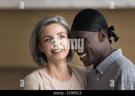Cheerful mature Caucasian woman standing close to beloved Black man Stock Photo