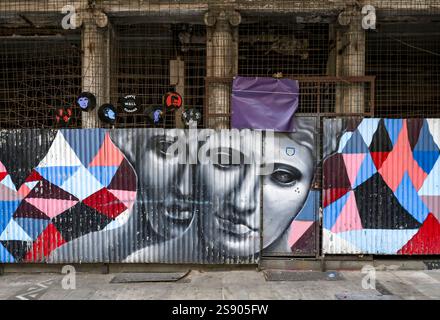 Street art featuring monochromatic faces on corrugated metal with geometric colorful patterns in an urban setting, showcasing creativity and modern Stock Photo