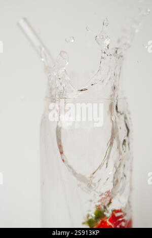 Strawberry dropped in water creating a splash with a reusable gl Stock Photo