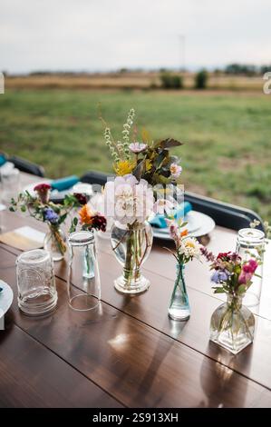Bud vases on a wooden table outside Stock Photo