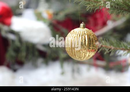A golden Christmas ball hangs on the tree outside Stock Photo
