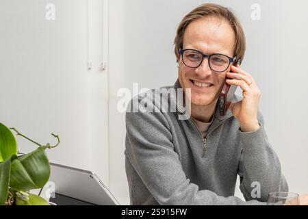 Smiling Entrepreneur Engaged in a Business Call at a Modern Workspace Stock Photo