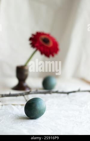 Natural Easter composition with a red flower, dyed eggs. Stock Photo