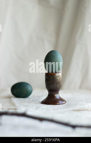 Green naturally dyed Easter egg in a rustic ceramic holder. Stock Photo