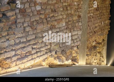 A corner of a room with an old brick wall illuminated by light coming from a glass door. Stock Photo