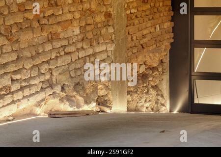 A partially ruined brick wall highlighted by artificial lighting with a small platform in front. Stock Photo