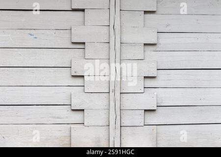 A fragment of a wooden plank wall painted in white with an interesting geometric pattern. Stock Photo