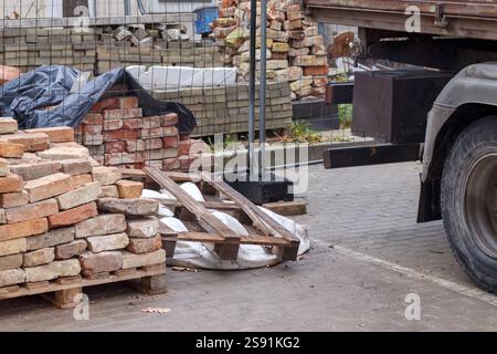 A construction site with bricks and a truck stacked on pallets. Stock Photo