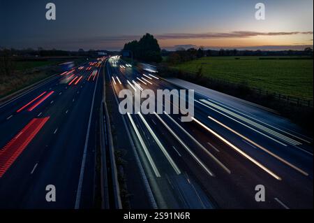 Light trails formed by traffic travelling towards and away from the camera, on the M6 motorway, at dusk on a winter evening. Stock Photo
