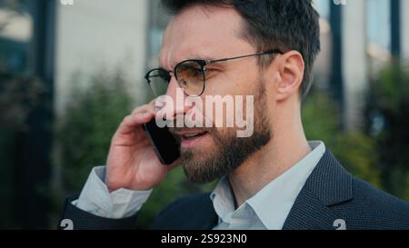 Caucasian businessman successful business entrepreneur commercial ceo employer chief walking on street talking mobile phone on way to work male busy Stock Photo