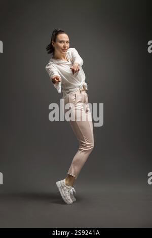 Young and beautiful dancer posing in studio at grey background Stock Photo