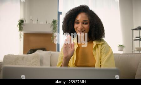 Happy African American woman smiling ethnic curly hair girl female homeowner talk with friend computer video chat talking to laptop web camera virtual Stock Photo