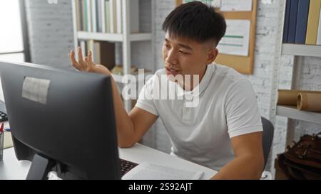 Young man working from home in bedroom talking at computer desk during indoor video call Stock Photo