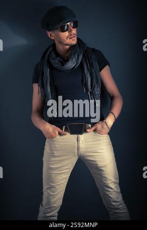 Handsome young man posing with hat, on blue background Stock Photo