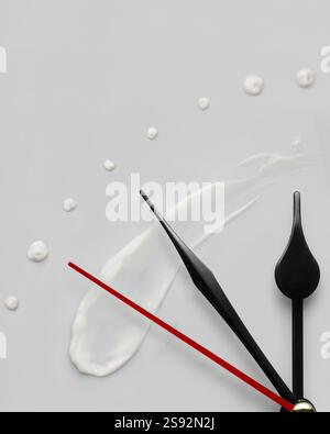 Creative concept photo of clock hands and cream on a grey background Stock Photo