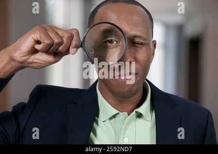 Handsome African American man looking through a large magnifying glass Stock Photo