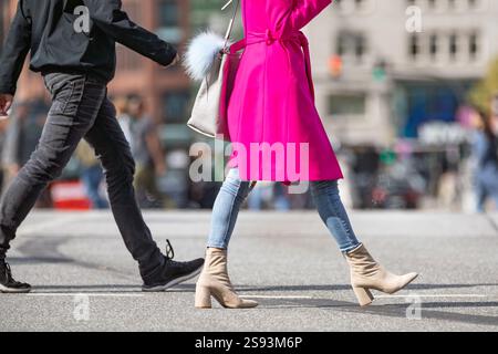 young woman wearing pink coat crosses the street Stock Photo
