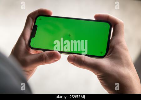 Hands of young man with cell phone and green screen on a sunny day. Stock Photo